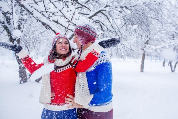 Couple câlins et s'amuser sous la neige qui tombe