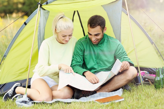 couple camping en forêt avec carte