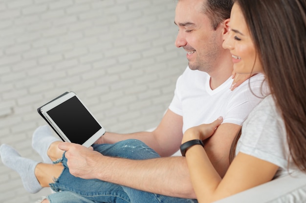 Couple sur le canapé avec tablette numérique