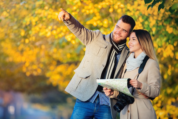 Couple avec carte et caméra dans l'allée d'automne ville.