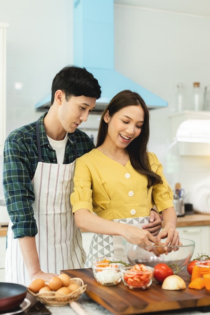 Photo un couple casse un œuf pour faire une omelette du matin à la maison