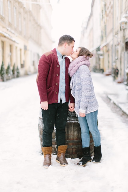 Couple caucasien heureux et romantique dans des chandails chauds marchant dans la ville d'hiver Lviv. Vacances, hiver, amour, boissons chaudes, gens