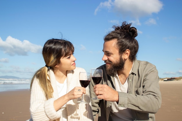Couple caucasien romantique buvant du vin rouge au bord de la mer