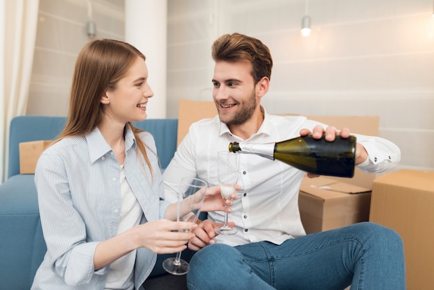 Couple célébrant avec champagne se déplaçant vers nouvel appartement.