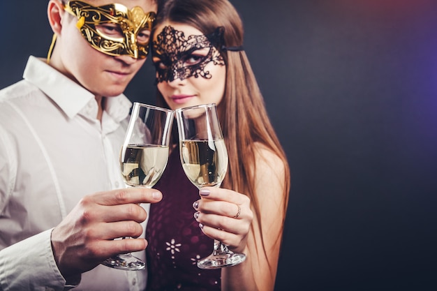 Couple célébrant le réveillon du Nouvel An buvant du champagne lors d'une soirée masquerade