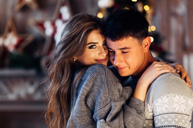 Couple en chandails gris élégants étreignant le temps de noël