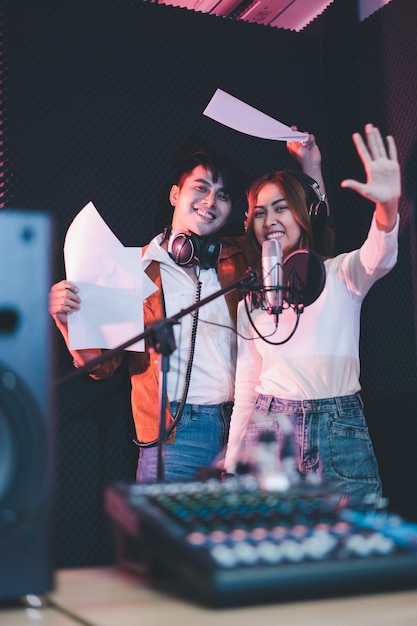 Couple de chanteurs asiatiques dans un studio d'enregistrement utilisant un microphone de studio avec passion dans un studio d'enregistrement musical