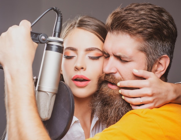 Couple de chanteurs chantant un producteur de son rock enregistrant une chanson dans un studio de musique sexy homme et femme chantant