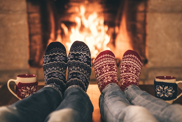 Couple en chaussettes de Noël près de la cheminée Homme et femme s'amusant ensemble Les gens se détendre à la maison