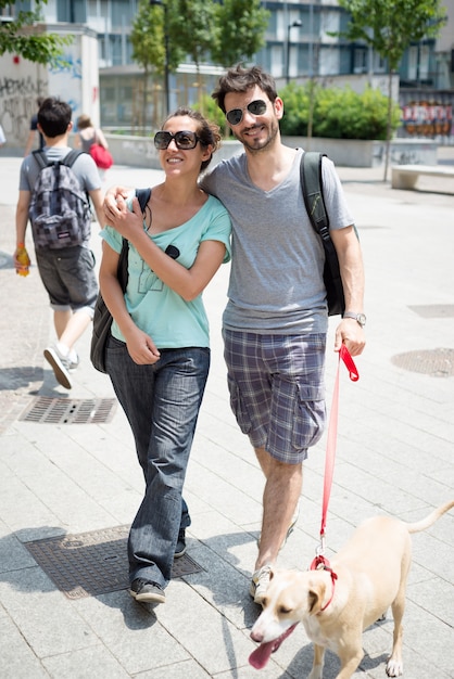 couple avec un chien qui marche dans la rue