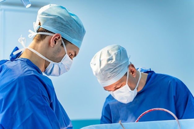 Couple de chirurgiens opérant dans des masques médicaux blancs. Opération de chirurgie d'urgence.