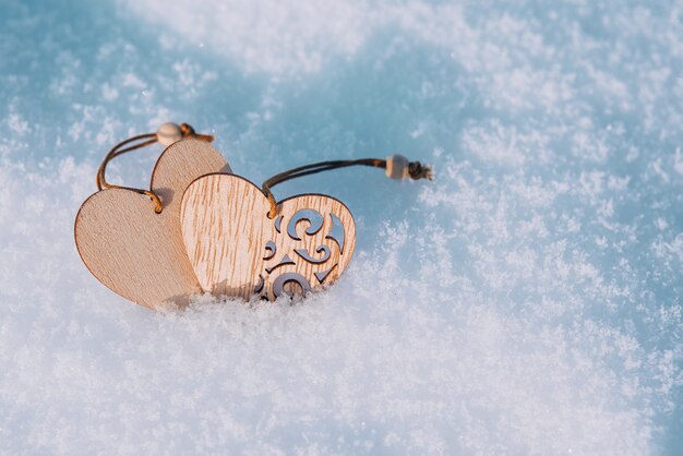 Couple de coeurs en bois dans la neige froide et glaciale du matin. Carte de voeux Saint Valentin. Symbole de l'amour