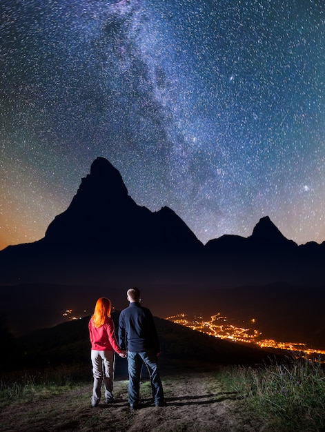 couple sur la colline et profiter de ciel étoilé la nuit