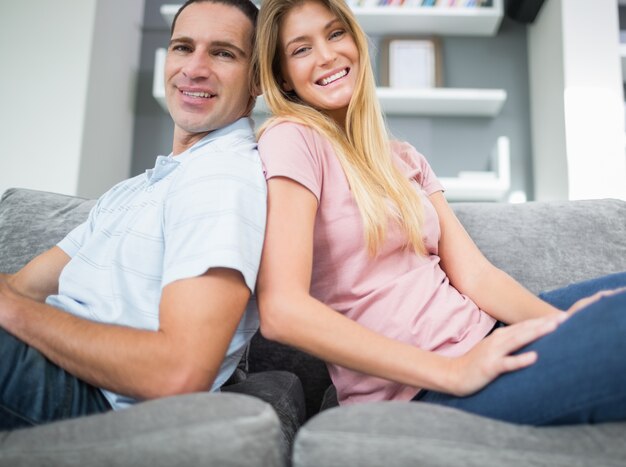 Couple de contenu assis dos à dos sur le canapé ensemble