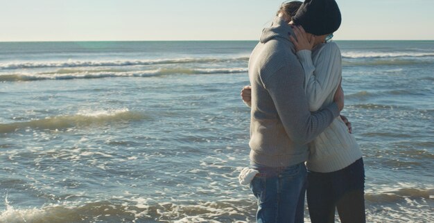 Couple cool riant et étreignant devant la plage lors d'une belle journée d'automne