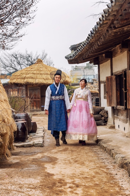 Un couple coréen dans des hanboks marchant dans un magnifique parc