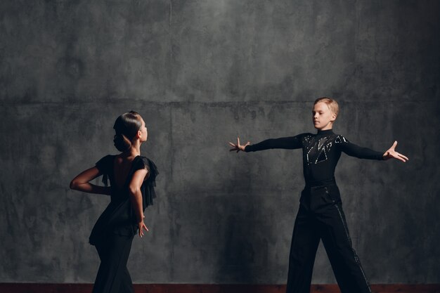 Couple en costumes noirs dansant dans la danse de la rumba de salle de bal.