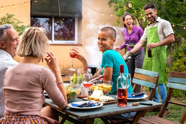 Un couple cuisinant sur le gril pour des amis Une fête au barbecue dans le jardin En plein air Des amis qui rient