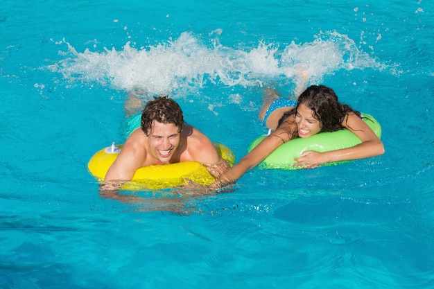 Couple dans des anneaux gonflables à la piscine