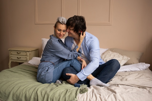 Couple dans la chambre assis sur le lit à la maison et étreindre.