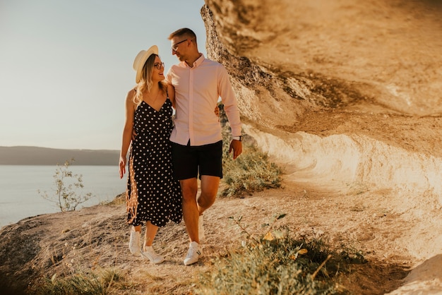 Couple dans un chapeau marche le long des rochers au-dessus de la falaise.