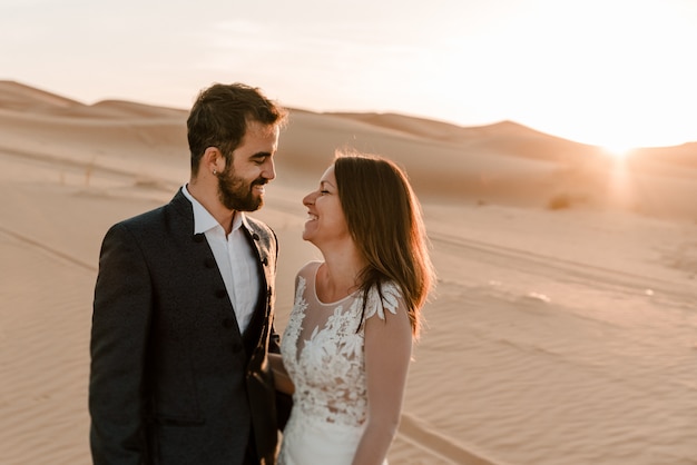 Un couple dans leurs robes de mariée dans le désert