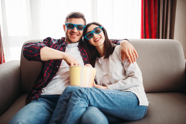 Couple dans des lunettes 3D regarder la télévision avec du pop-corn