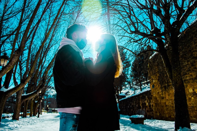 Couple dans la neige par une journée ensoleillée dans une forêt avec arbres et ciel bleu