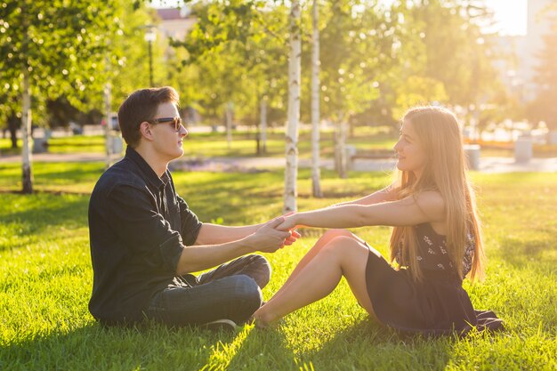 Couple dans le parc assis sur l'herbe, passez un bon moment ensemble