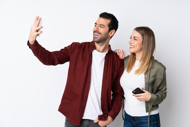 Couple dans la Saint-Valentin sur un mur isolé faisant un selfie avec le mobile