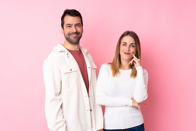 Couple dans la Saint-Valentin sur mur rose isolé souriant avec une douce expression