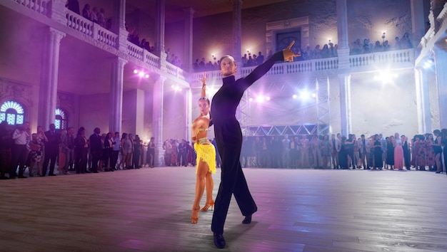 Photo couple de danseurs exécutent la danse latine sur une grande scène professionnelle danse de salon