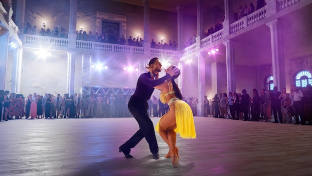 Photo couple de danseurs exécutent la danse latine sur une grande scène professionnelle danse de salon