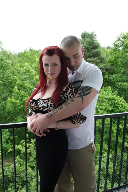 Photo un couple debout sur le balcon contre des arbres.