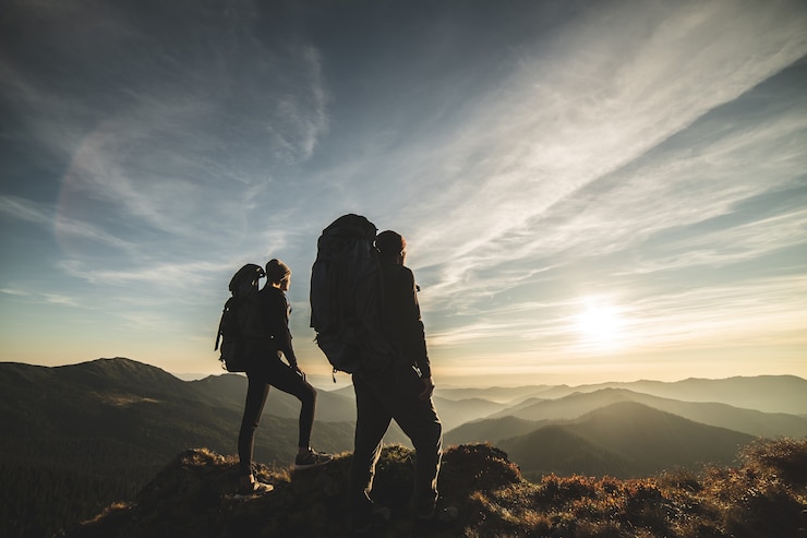 Photo le couple debout sur la montagne avec un fond de coucher de soleil pittoresque
