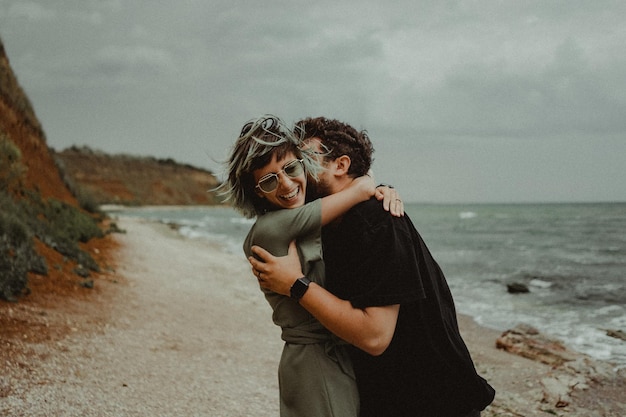 Photo un couple debout sur la plage contre le ciel