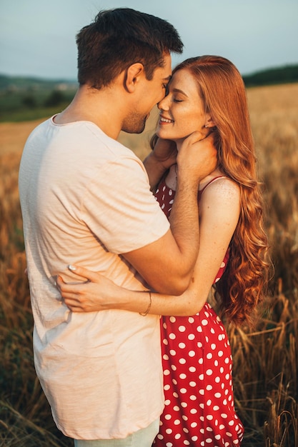 Couple debout près de l'autre dans le champ de blé loin de la ville après un baiser la nature