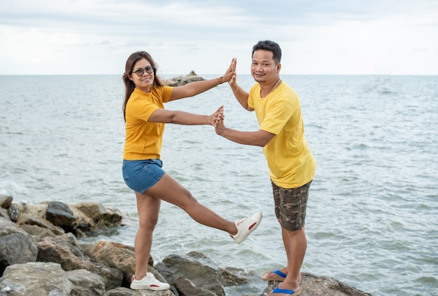 Couple debout sur un rocher près de la mer