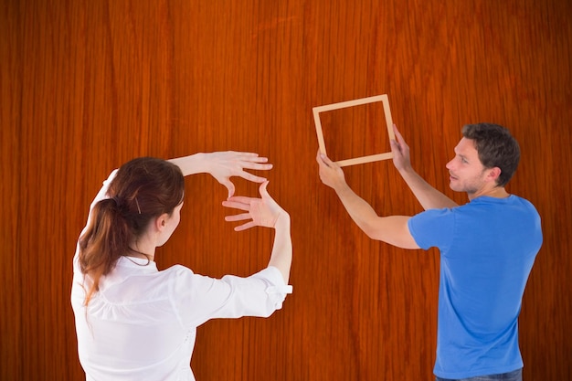 Photo couple décidant d'accrocher une photo contre une table en bois de chêne