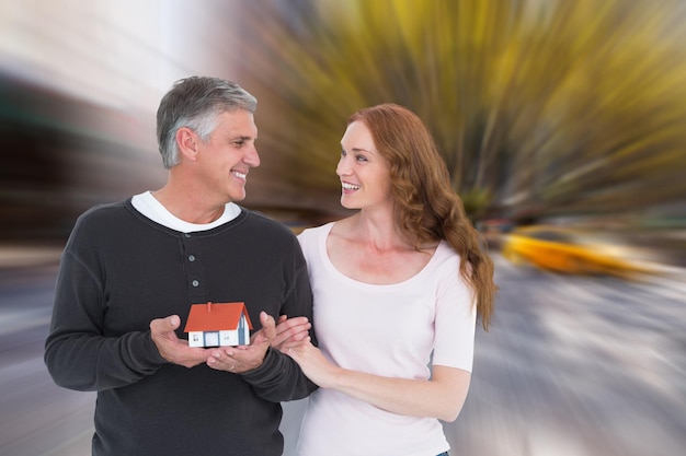 Couple décontracté tenant une petite maison contre la rue floue de new york