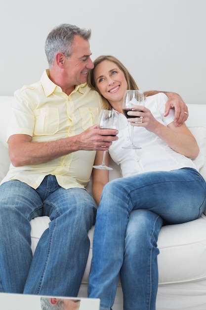 Couple décontracté avec des verres à vin assis sur le canapé