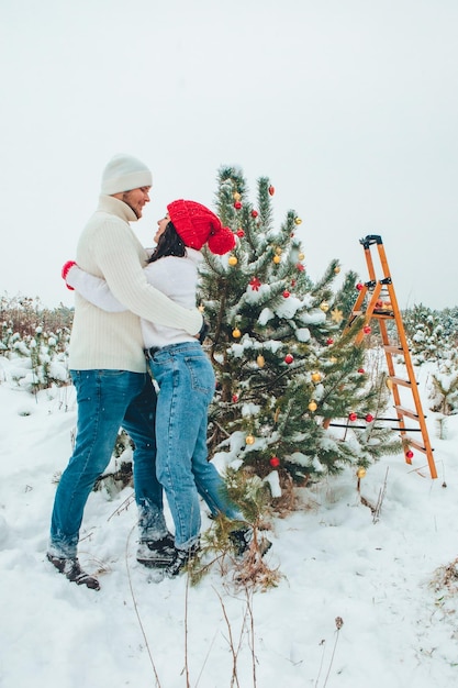 Couple décorant le sapin de Noël à l'extérieur