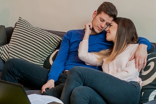 Couple détendu se serrant et s&#39;asseyant sur un canapé dans un salon. Beau couple de détente couple jeune sur le canapé amoureux