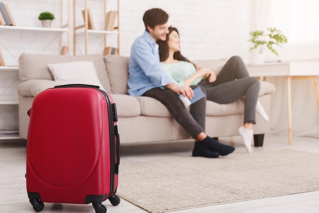 Couple détente sur canapé avec valise au premier plan