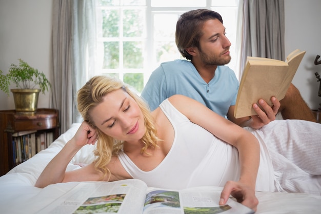 Couple de détente sur le lit en lisant des livres