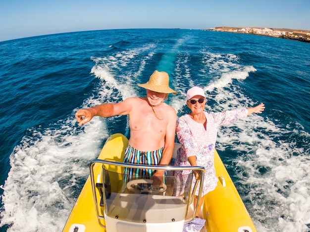 Couple de deux personnes âgées heureuses et personnes mûres utilisant et conduisant un petit bateau ou un canot