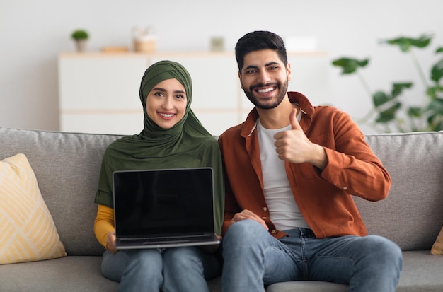 Couple du Moyen-Orient montrant un ordinateur portable avec un écran vide à l'intérieur