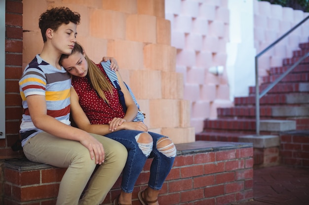 Couple d'école bouleversé assis près des marches