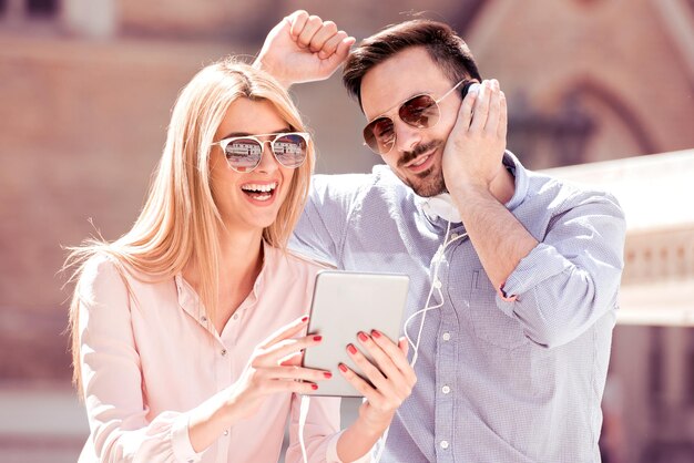 Couple écoutant de la musique avec une tablette en ville