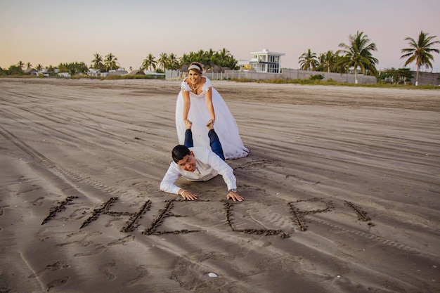 Photo un couple écrit dans le sable avec le mot qu'ils ont écrit dans le sable.